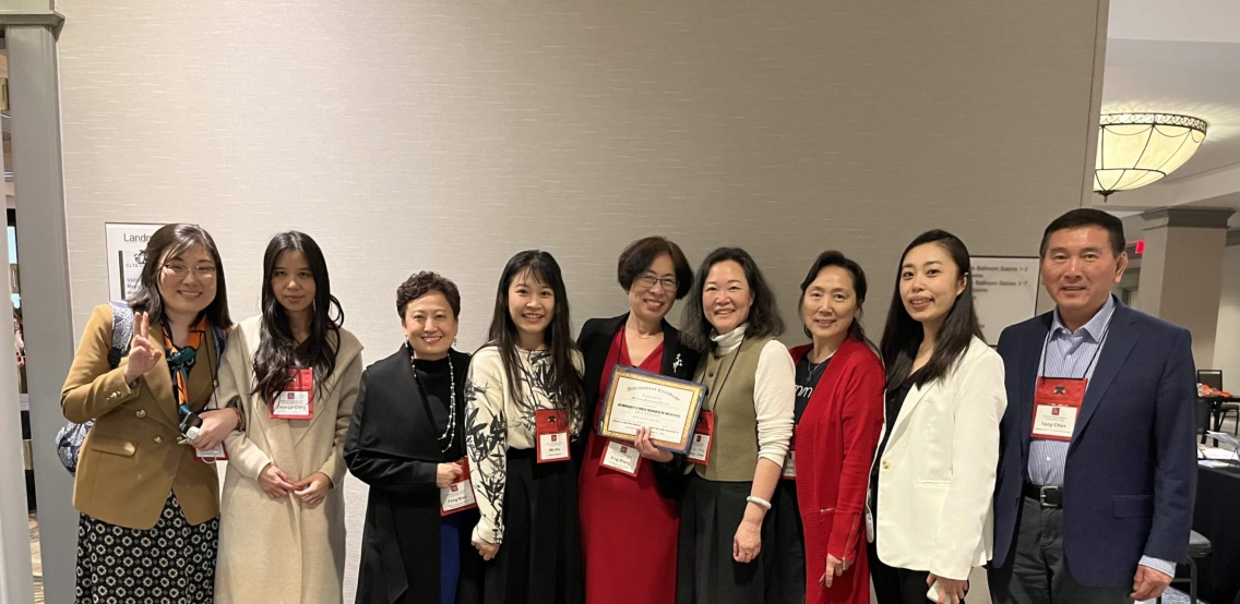 A group of teachers stands with woman holding award. 