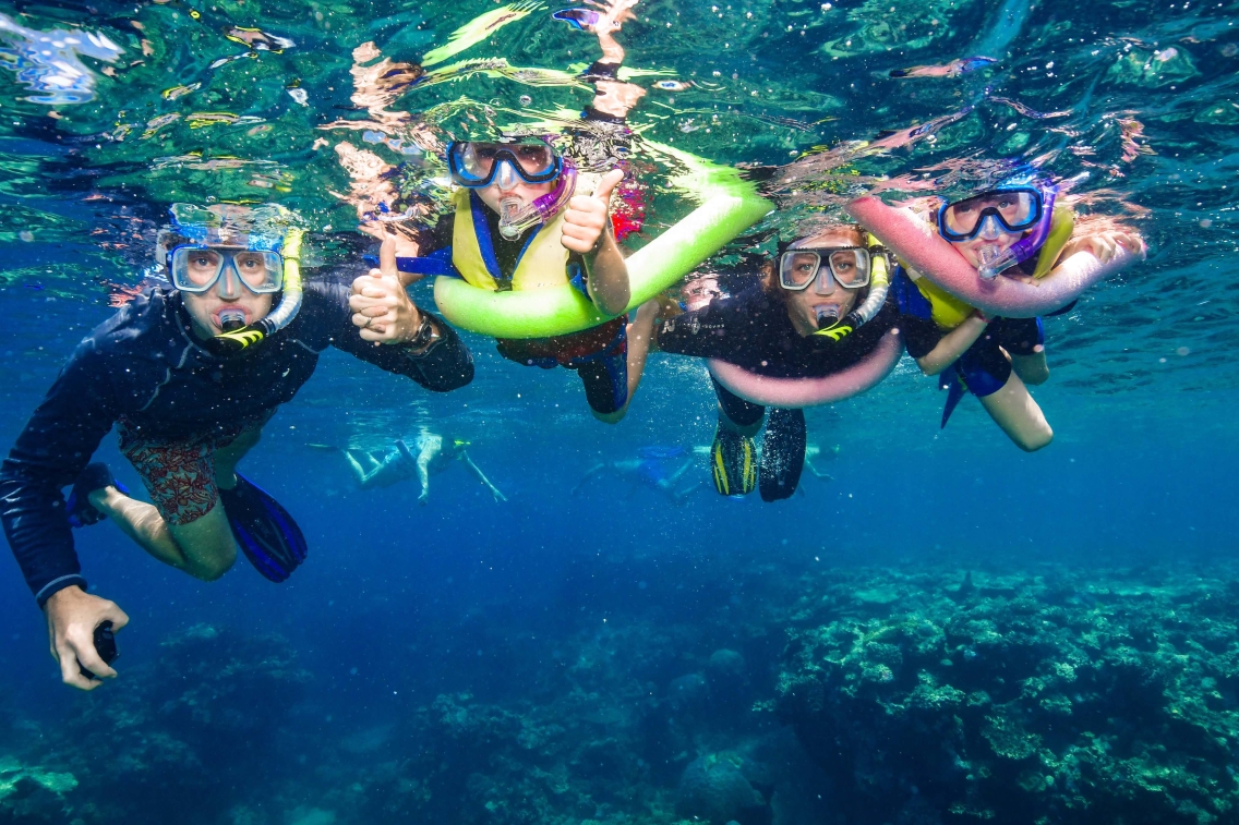 A family poses underwater in snorkeling gear.