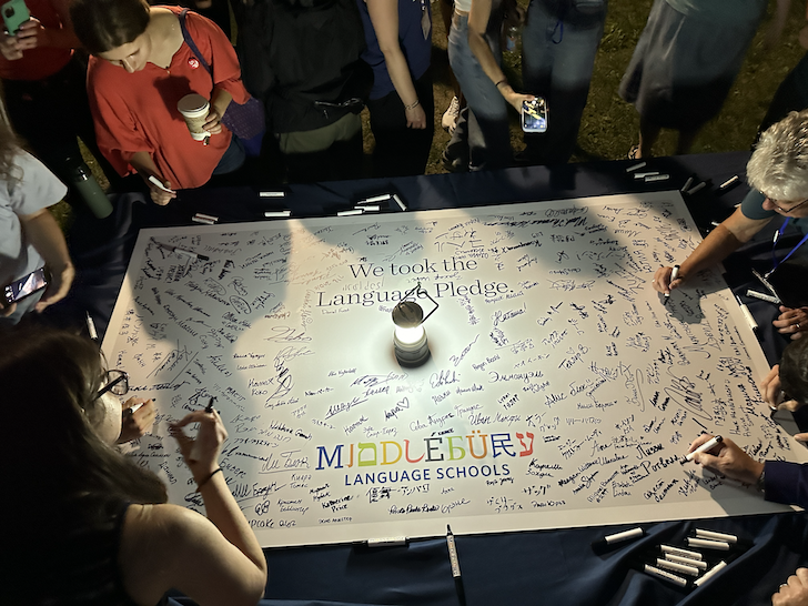 Students sign the Language Pledge, a lantern illuminating the sign.
