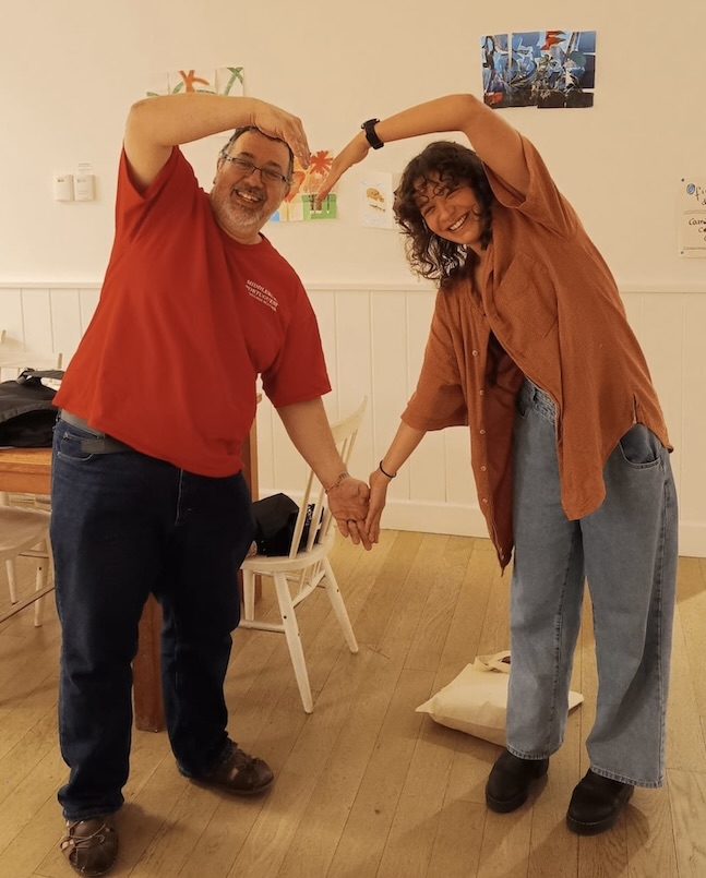 School of Portuguese director and student pose with arms forming a heart.
