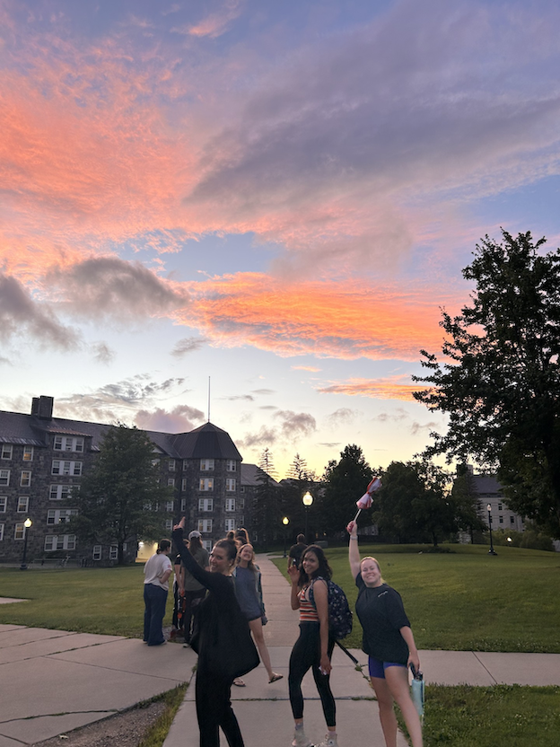 Women point their umbrellas at a sunset.
