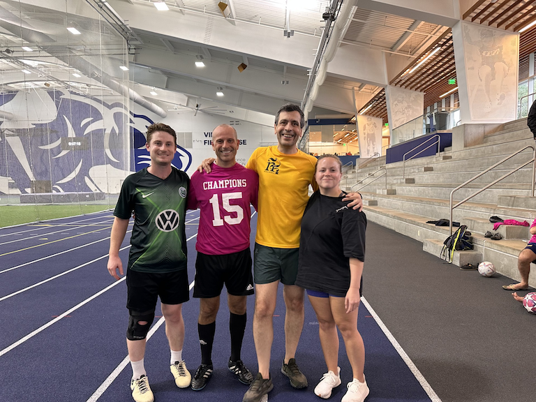 A group of students and teachers pose in soccer uniforms.