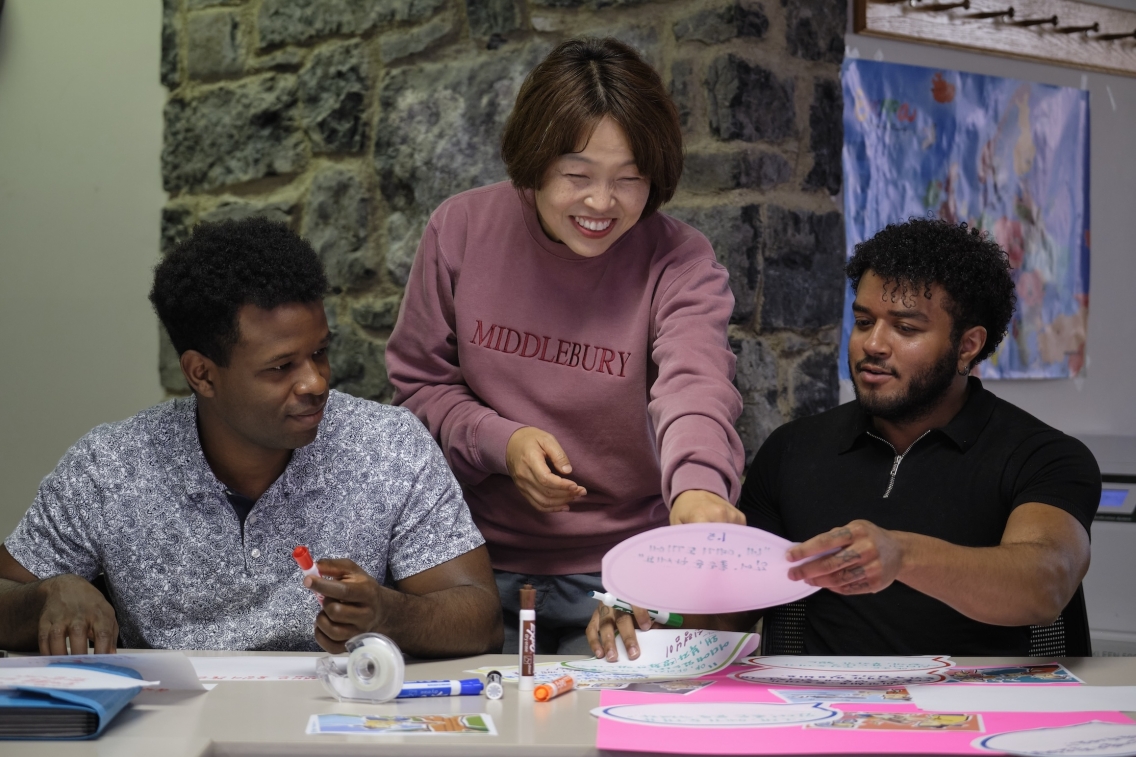 Two students work with their teacher on a project.