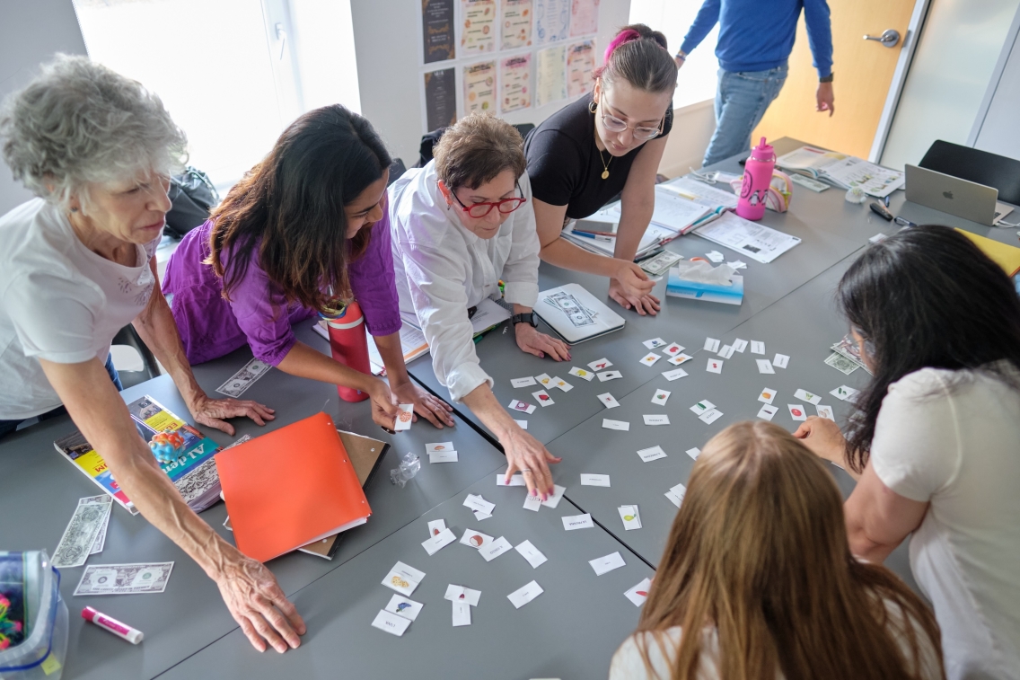Students work with paper slips together at a table in class.