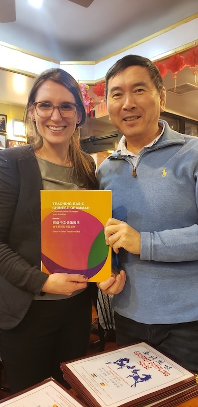 A man and a woman smile with a book.