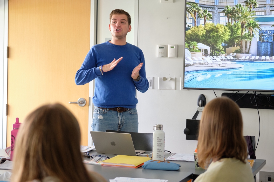 a man in a blue sweater teaches an Italian class. 