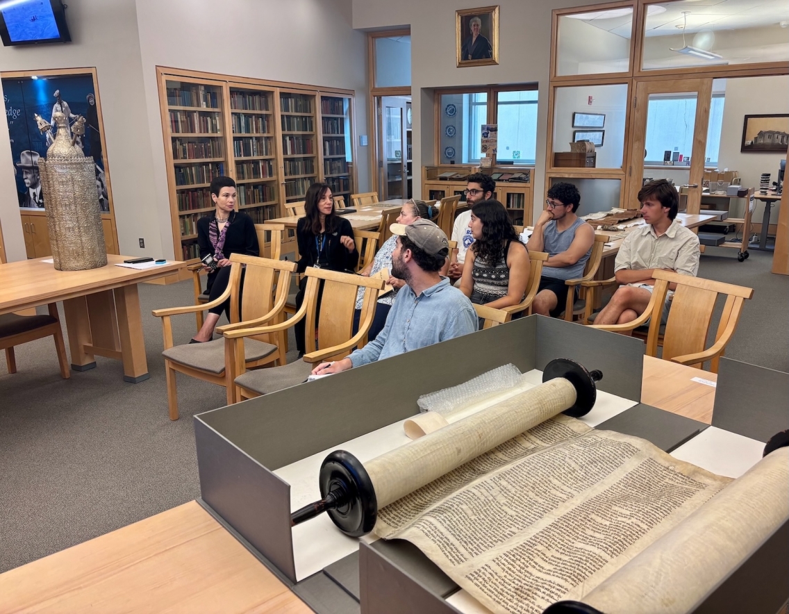 A group of students discusses primary Biblical Hebrew resources in a library.