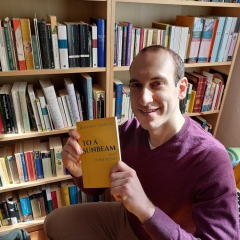 A man holds up a book of poetry. 