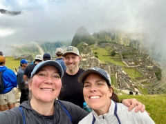Three friends pose with Machu Picchu in the background. 
