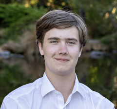 A student in a white dress shirt smiles at the camera. 