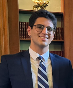 A man in a suit and tie smiles at the camera. 