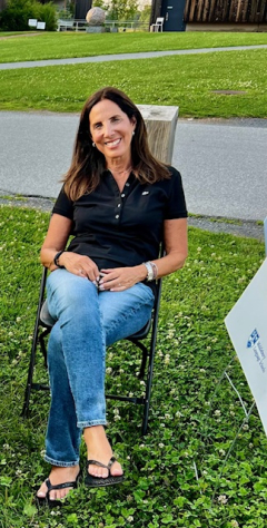 A woman in a black polo shirt smiles at the camera. 