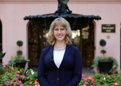 A woman in a navy suit smiles at the camera. 
