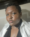 A student looks at the camera in a black shirt and white jacket.