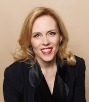 a woman in a velvet jacket smiles at the camera
