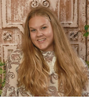 A woman with long blonde hair smiles at the camera.