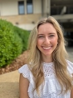 A woman in a white shirt smiles at the camera