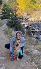 A woman in a gray sweatshirt smiles with her dog