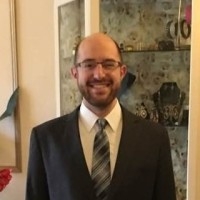 A man in a suit and tie smiles at the camera.