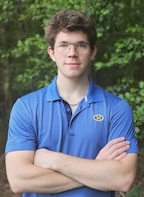 A man in a blue button up smiles at the camera.