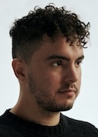 A man in a black t-shirt looks off to the side.