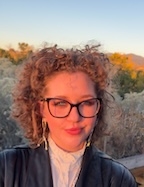 A woman smiles at the camera at golden hour.