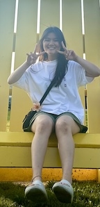 A woman makes peace signs sitting in a yellow chair