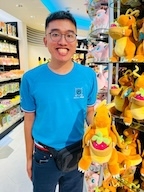 a man with a dragon stuffed animal smiles at the camera.