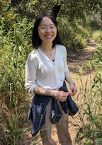 A woman in a white shirt smiles at the camera.