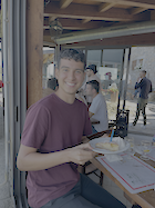A man in a red shirt holds a piece of cake.
