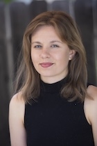 A woman in a black tank top smiles at the camera. 