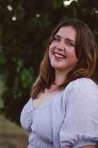 A woman in a white blouse smiles at the camera. 