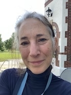 A woman in a black turtleneck smiles at the camera.