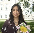 A woman holding flowers smiles at the camera. 