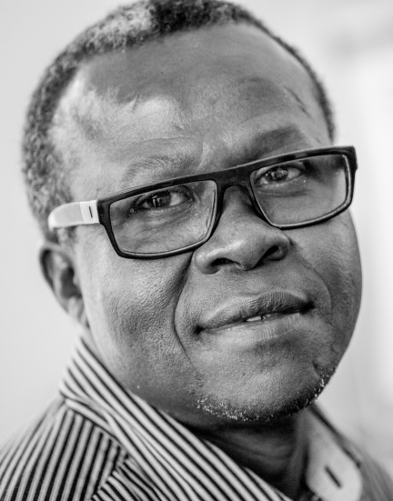 A man with glasses looks at the camera.