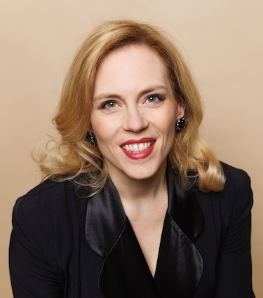 A woman in a velvet jacket smiles at the camera. 