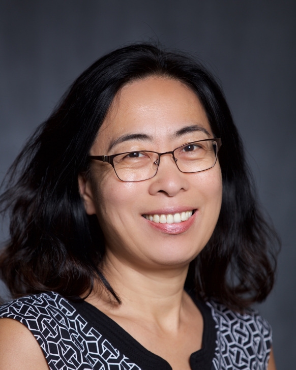 A woman in a black and white shirt smiles at the camera. 