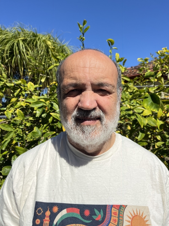 A man in a white t shirt looks at the camera. 