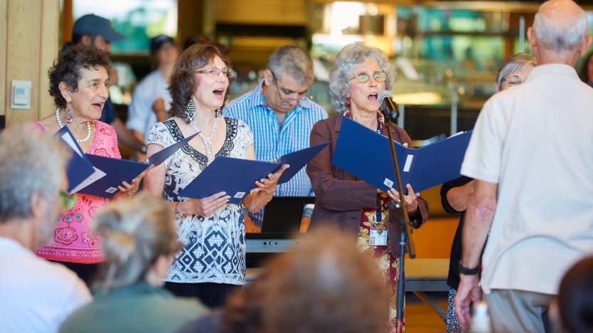 Four women sing, standing in front of instructor.