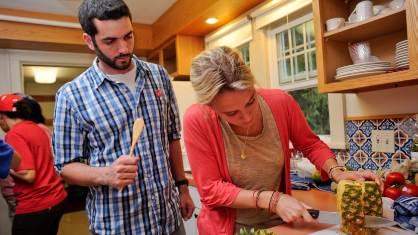 Two spanish language school students cutting a pineapple.