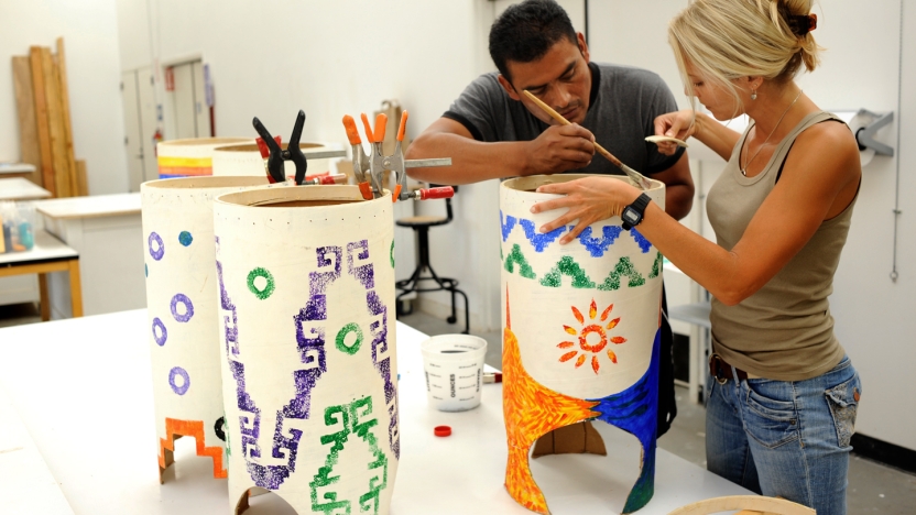 Two spanish language school students painting sculptures.