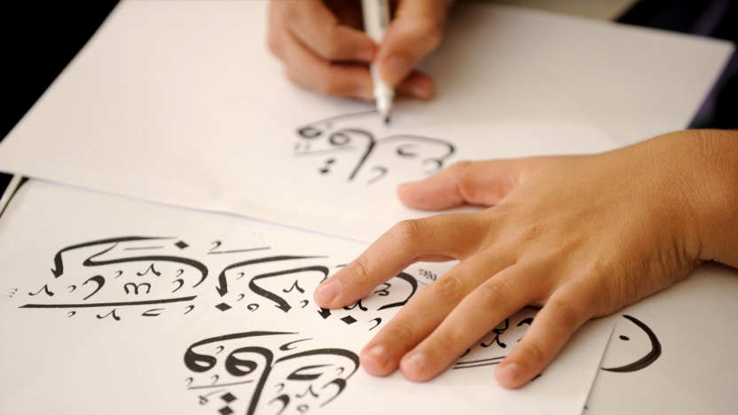 Student writing calligraphy on large paper.