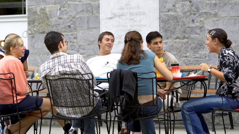 Seven spanish language school students eating lunch outside and conversing.