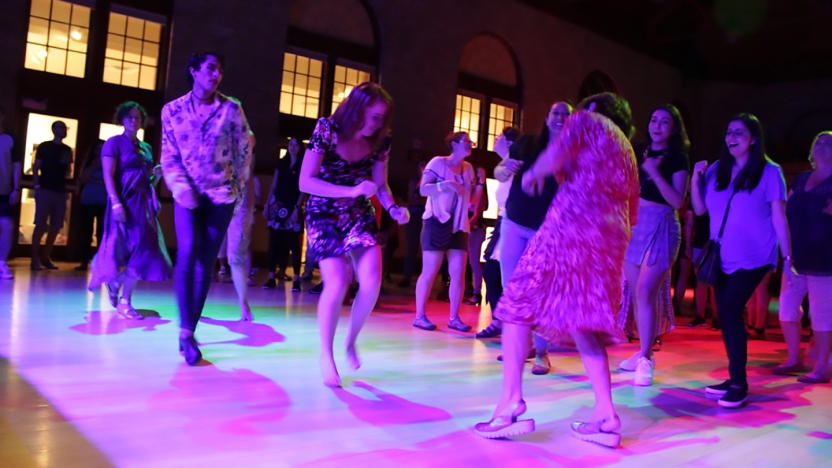 Large group of spanish language school students dancing in large group.