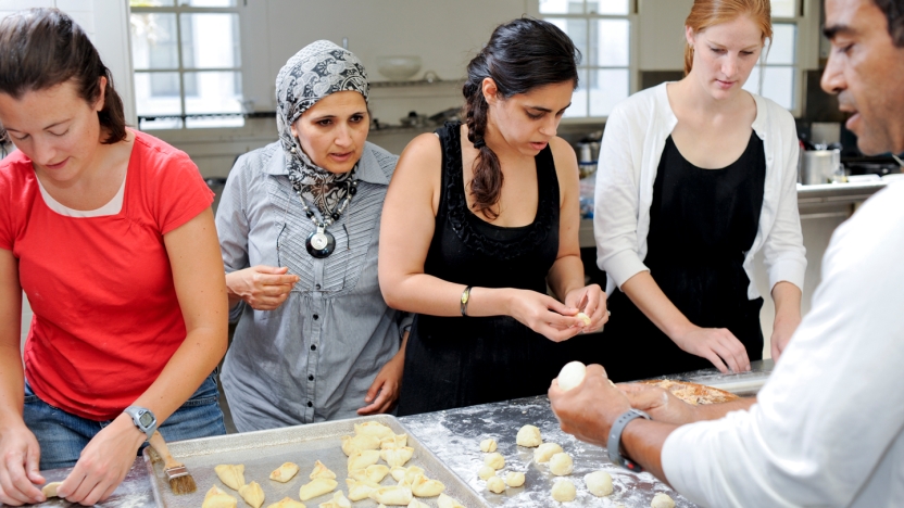 Four students learn to cook from an instructor.