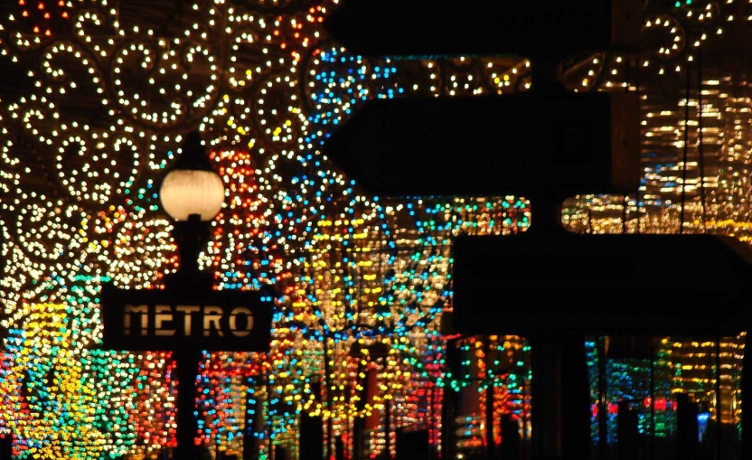 Paris metro street sign with sparkling lights in background.