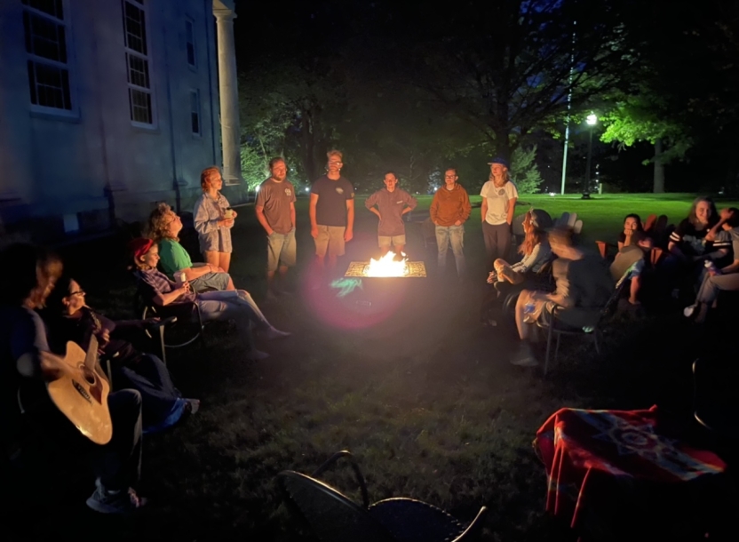 The Abenaki students sit outside in the dark by the fire.