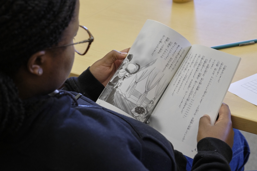 A woman reads a book in Japanese- pictures and Japanese characters.