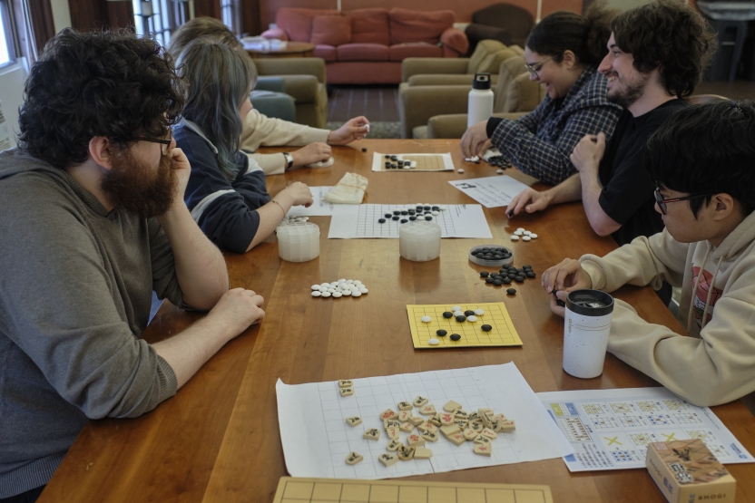 Students sit at a long table playing various Japanese games.