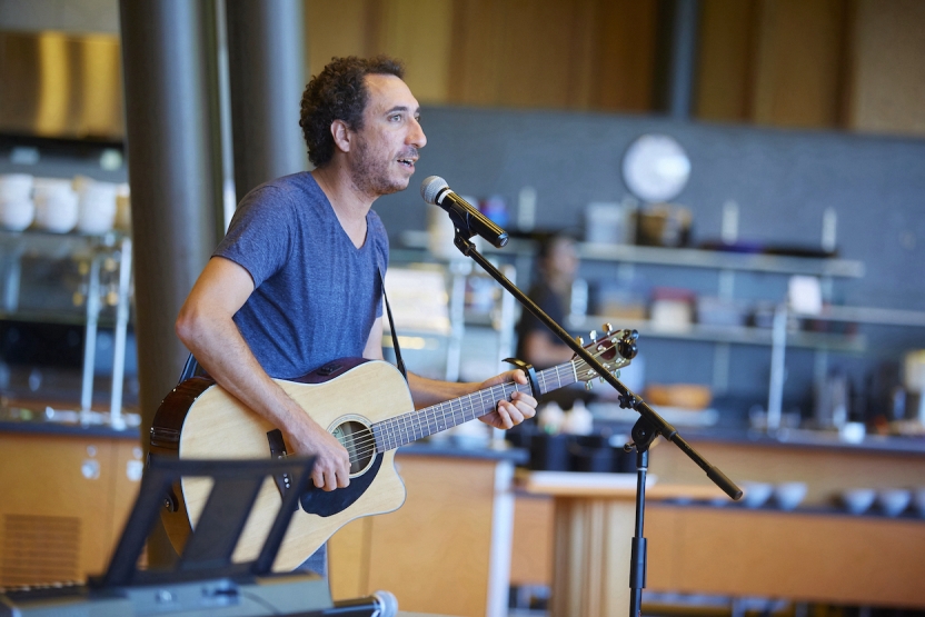 A man sings while playing guitar in front of a crowd. 